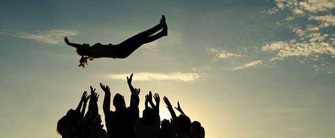 siluetas de un grupo de personas levantando a una mujer en el aire