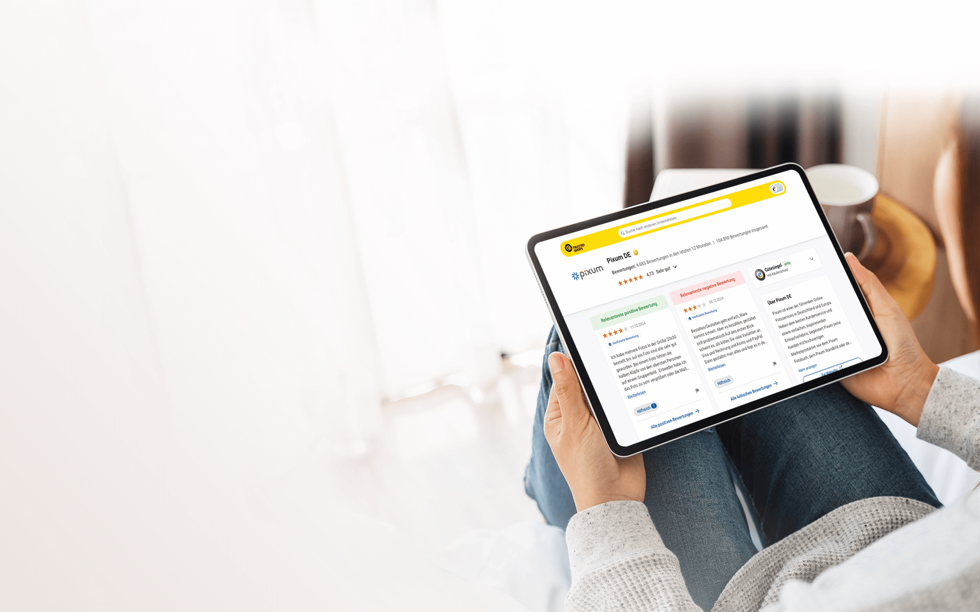 Una persona sostiene una tablet donde se ve el perfil de opiniones de la tienda online Pixum